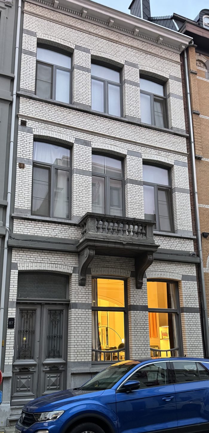 Foto van een rijwoning met drie verdiepingen, van op straat genomen.